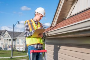 Home,inspector,standing,on,a,ladder,and,providing,an,inspection