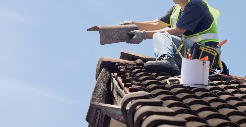 Worker,man,repairing,eaves,and,tile,of,the,old,roof.