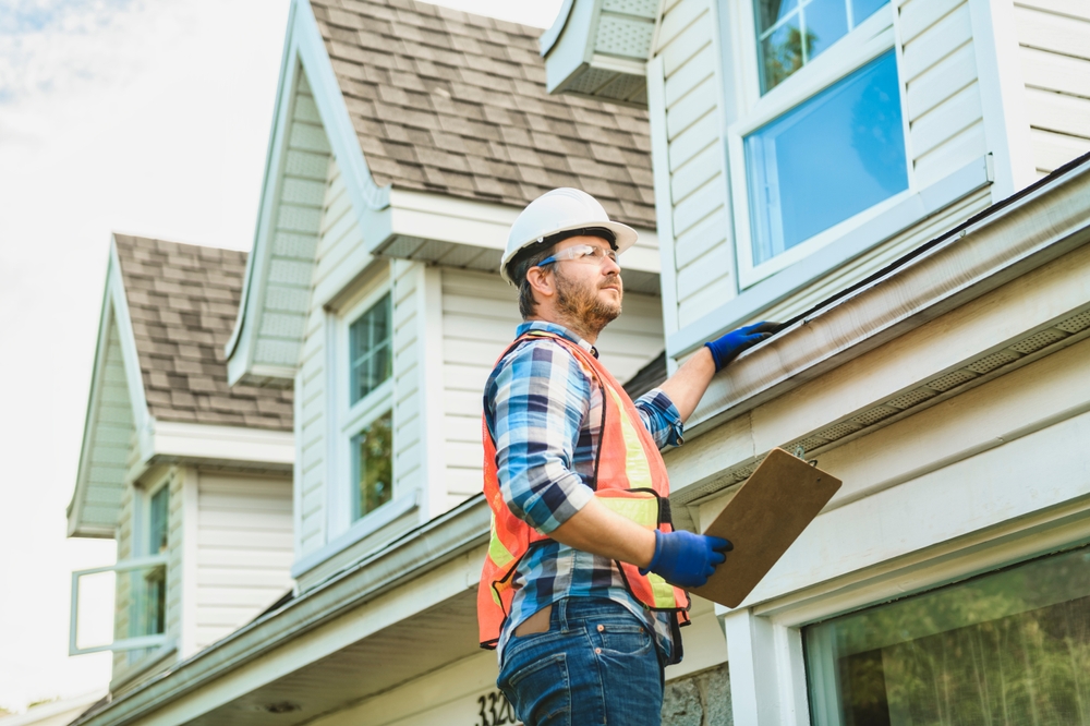 A,man,with,hard,hat,standing,on,steps,inspecting,house