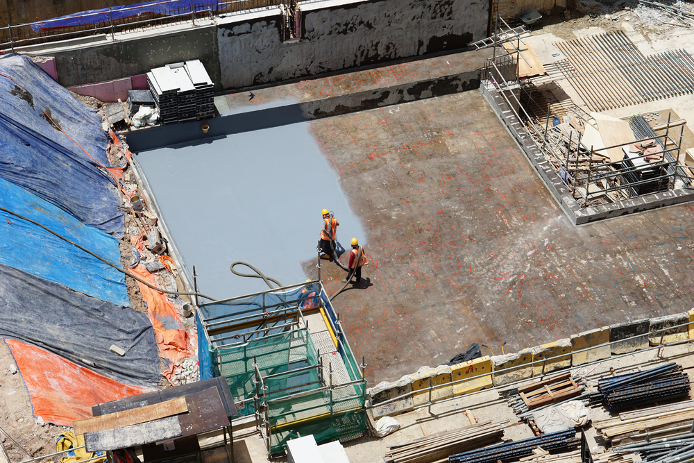 Construction,worker,coating,epoxy,spray,paint,at,basement,floor,slab